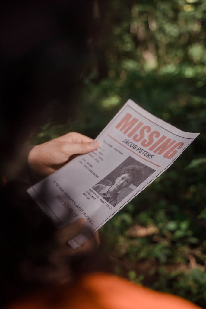Yahoo News Close-up of a missing person poster being held in a forest environment.