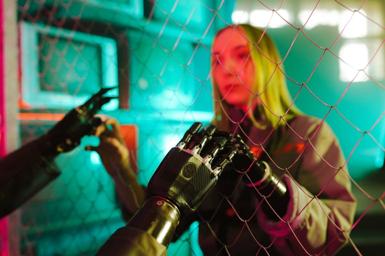 Technology: Shaping the Modern World and the Future of HumanityA woman interacts with a robotic hand through a fence under neon lights.