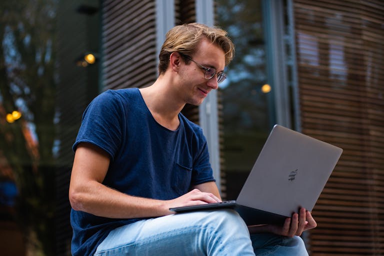 Nova Scola: Redefining Modern Education for the 21st CenturyA young man sitting outdoors in Leiden, Netherlands, working on a laptop.