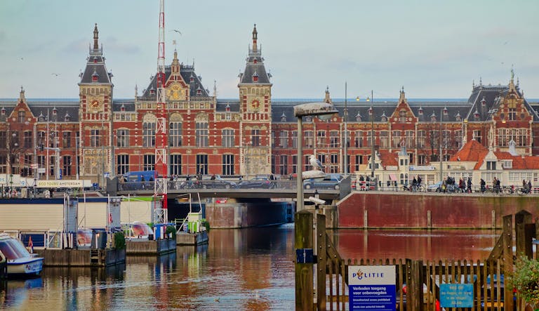 Couples in Amsterdam: Where Love Meets Desire Scenic view of Amsterdam Centraal station and canal, capturing local architecture.