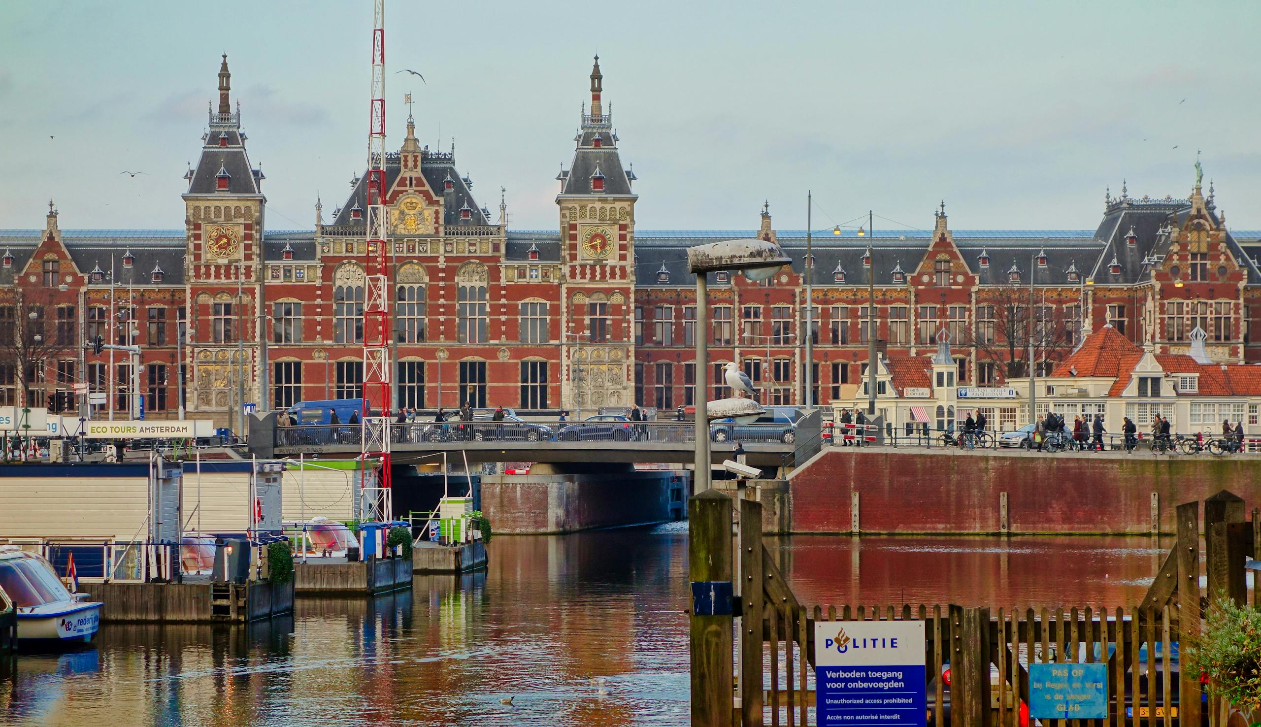 Couples in Amsterdam: Where Love Meets Desire Scenic view of Amsterdam Centraal station and canal, capturing local architecture.