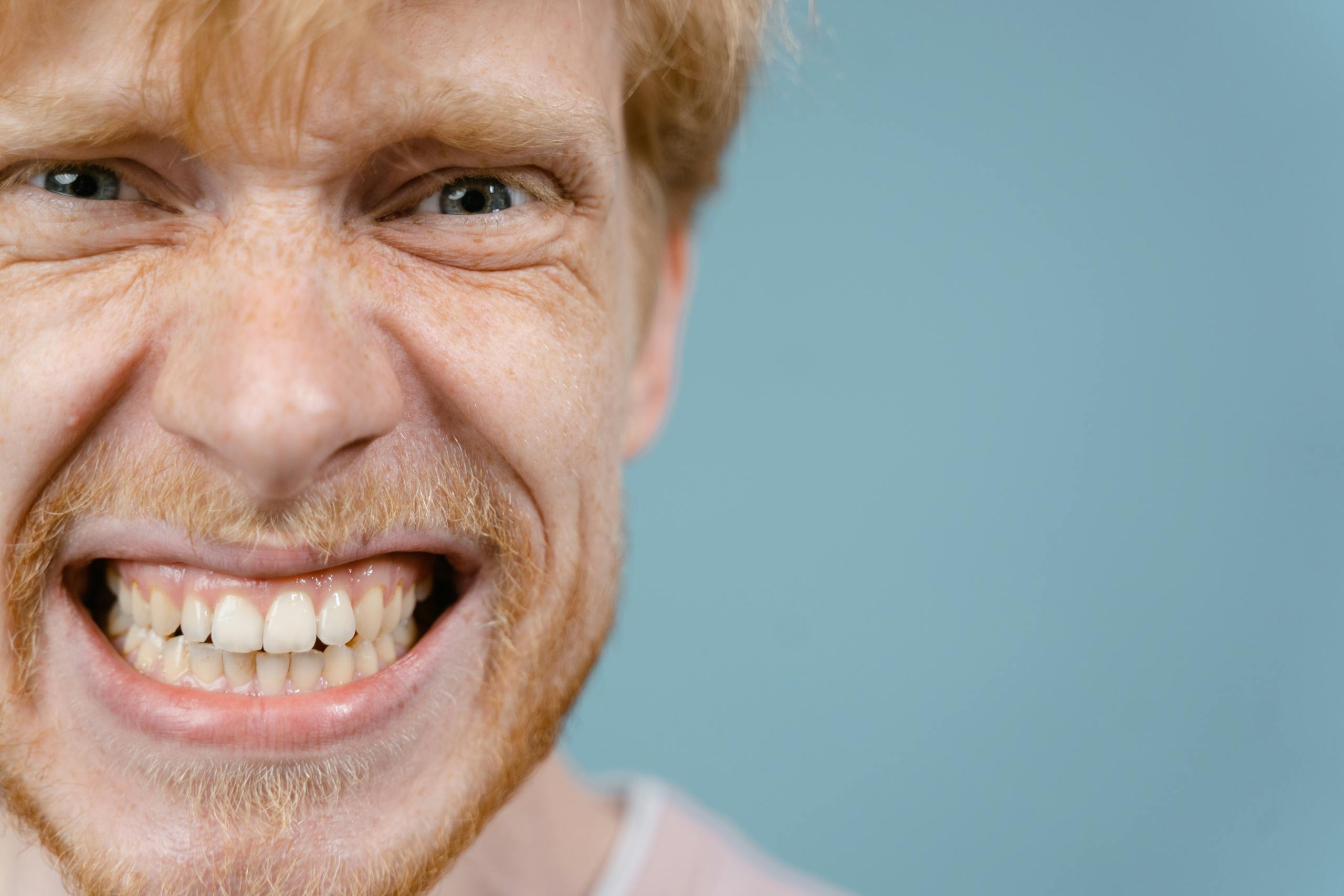 Wynonna Judd Performance Reactions A close-up portrait of a man with a wacky and intense facial expression against a blue background.