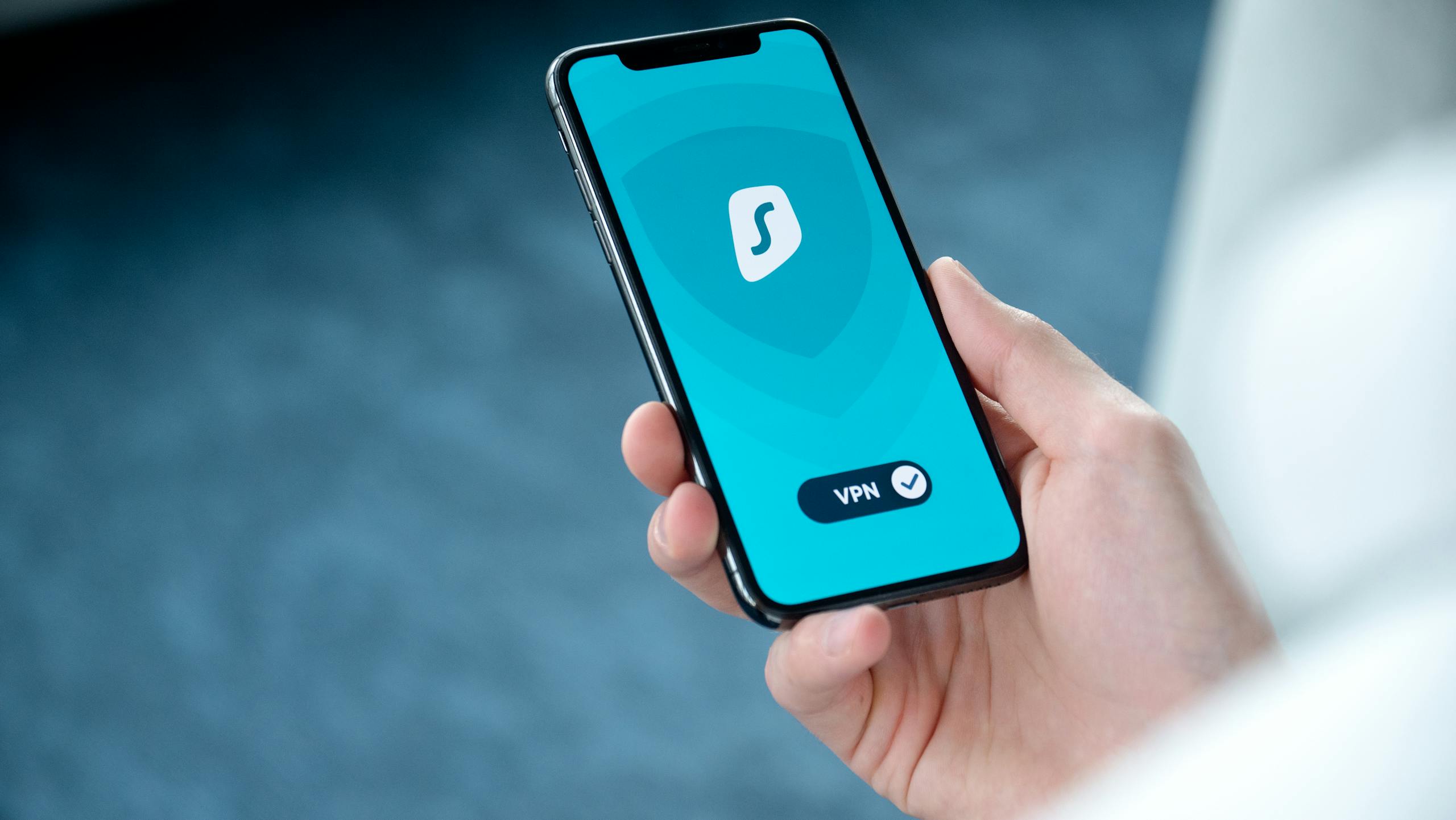 Juntos Seguros A hand holding a smartphone displaying a VPN app screen for secure online browsing.