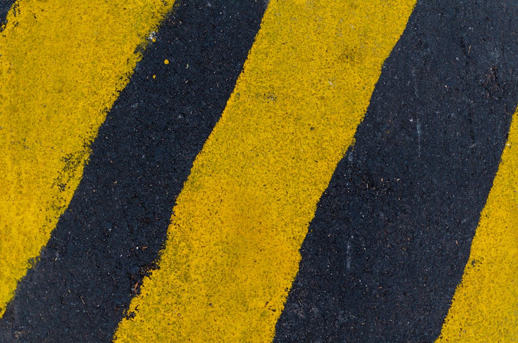 ReadSpeak A high-angle close-up of yellow and black road markings on asphalt surface.