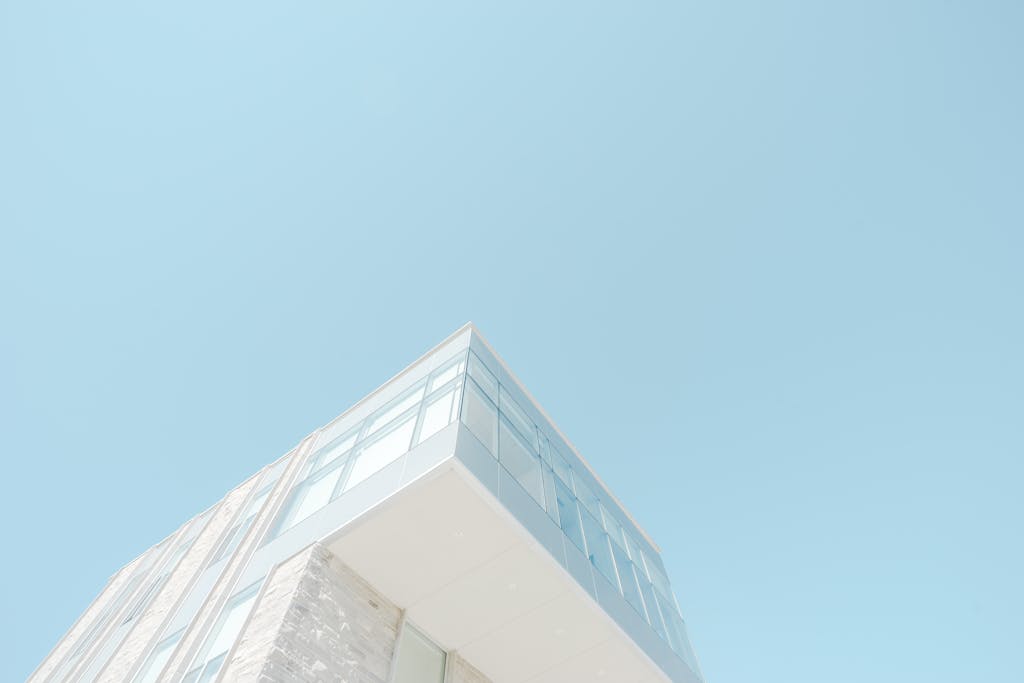 ventsMagazine A low-angle shot of a modern building with a glass facade against a bright blue sky in London, Canada.
