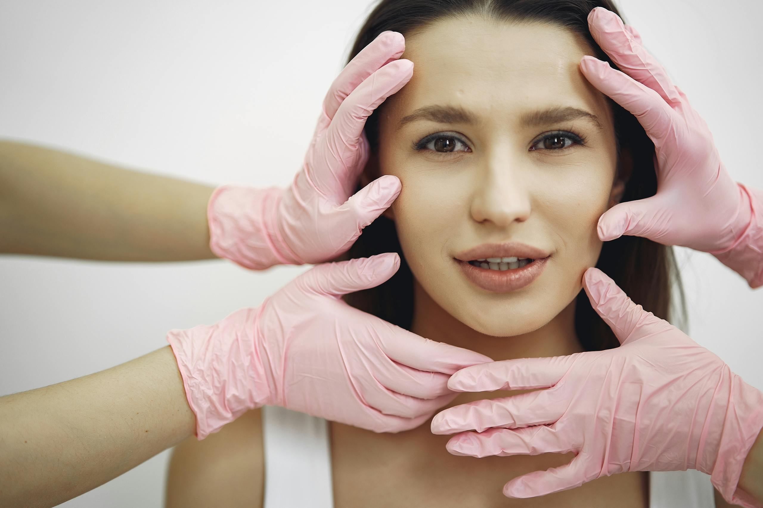 Britney SpearsA woman receiving a facial treatment, hands in gloves gently touching her face indoors.