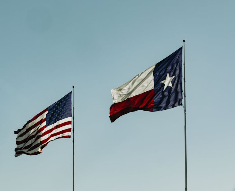 Texas Hunting Forum: The Ultimate Guide for Hunters in the Lone Star StateAmerican and Texas flags waving under a clear blue sky, symbolizing patriotism and freedom.
