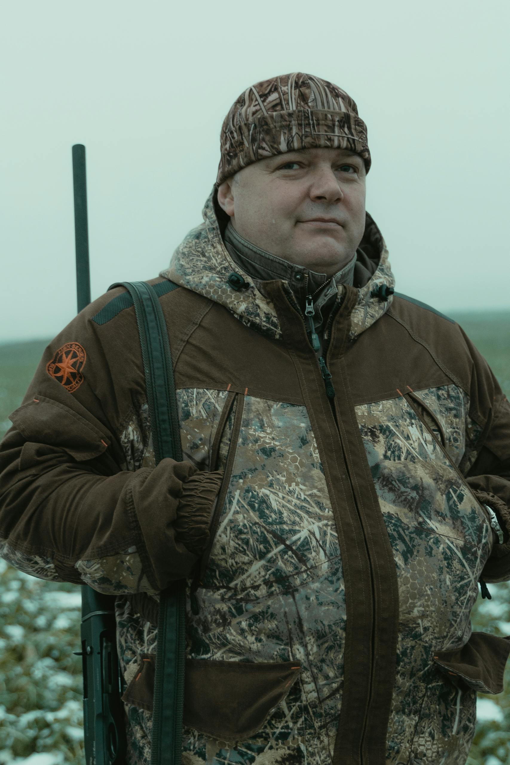 Texas Hunting Forum: The Ultimate Guide for Hunters in the Lone Star StateAn adult hunter in camouflage stands outdoors with a rifle, ready for the hunt.