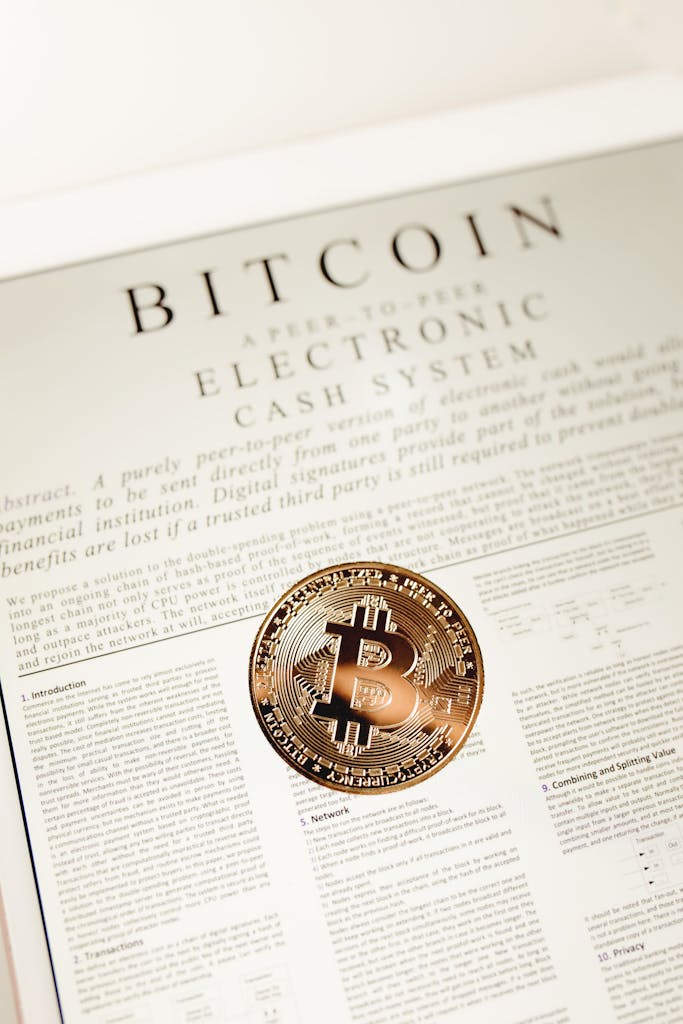 Bitcoin coin placed on a white paper document explaining electronic cash system.