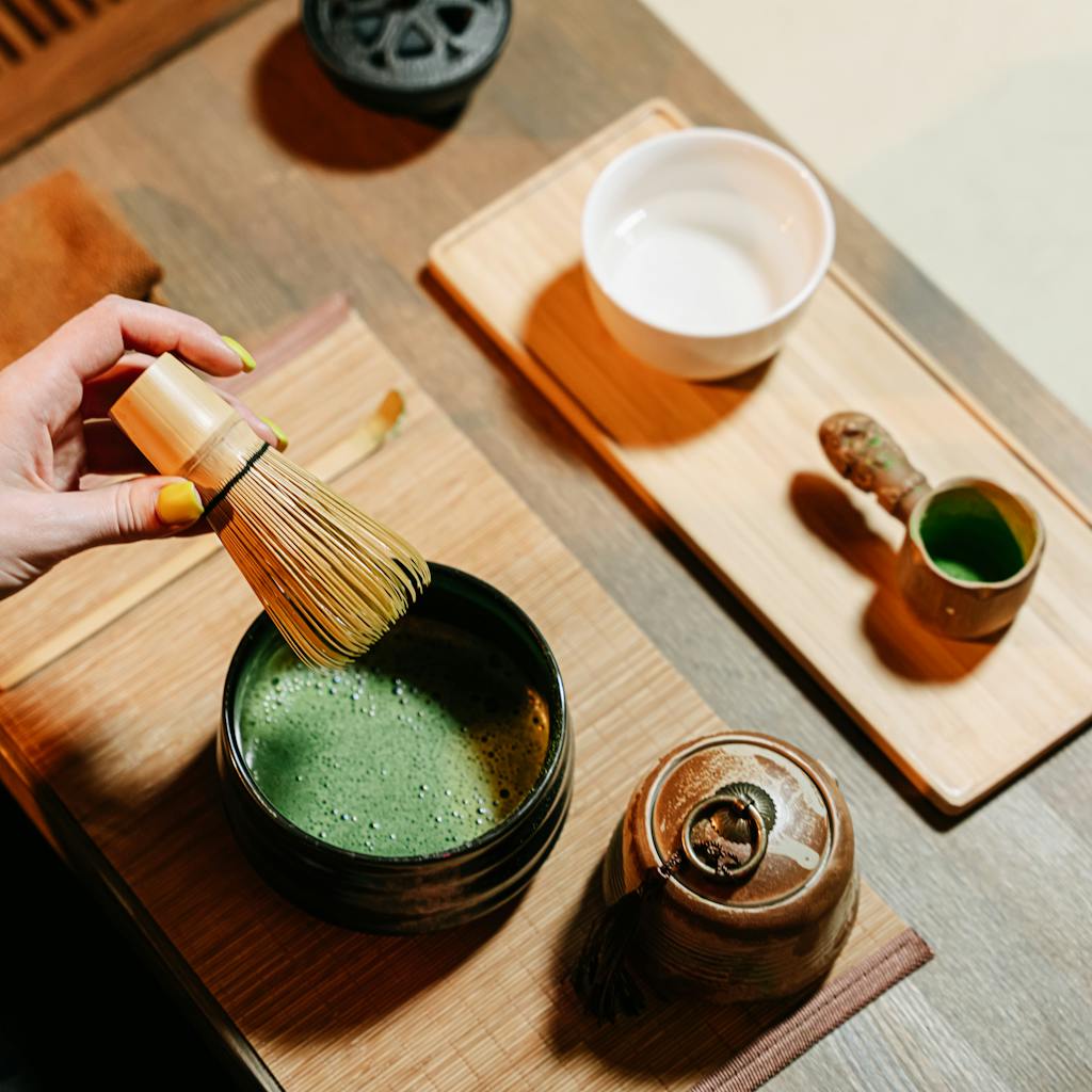 Close-up of a tea ceremony with matcha preparation tools on a wooden table.