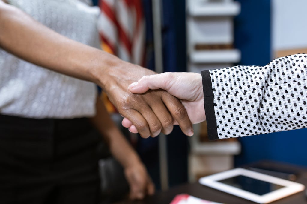 JuntosSeguros Close-up of two professionals shaking hands in a business environment.