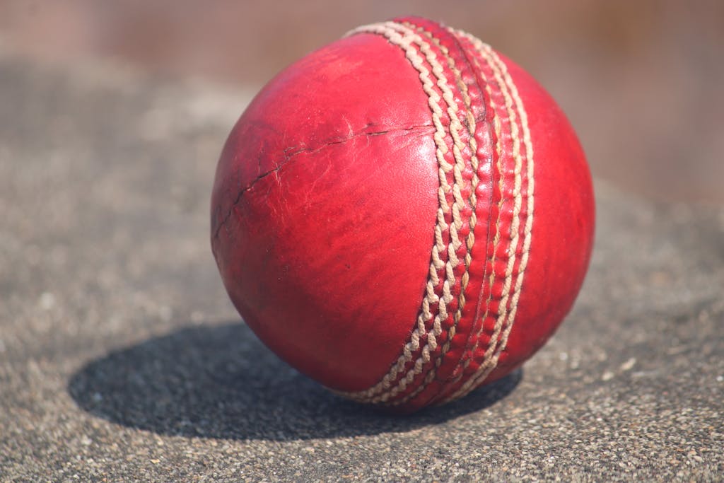 Pak vs Ind Detailed view of a textured red cricket ball outdoors in sunlight.