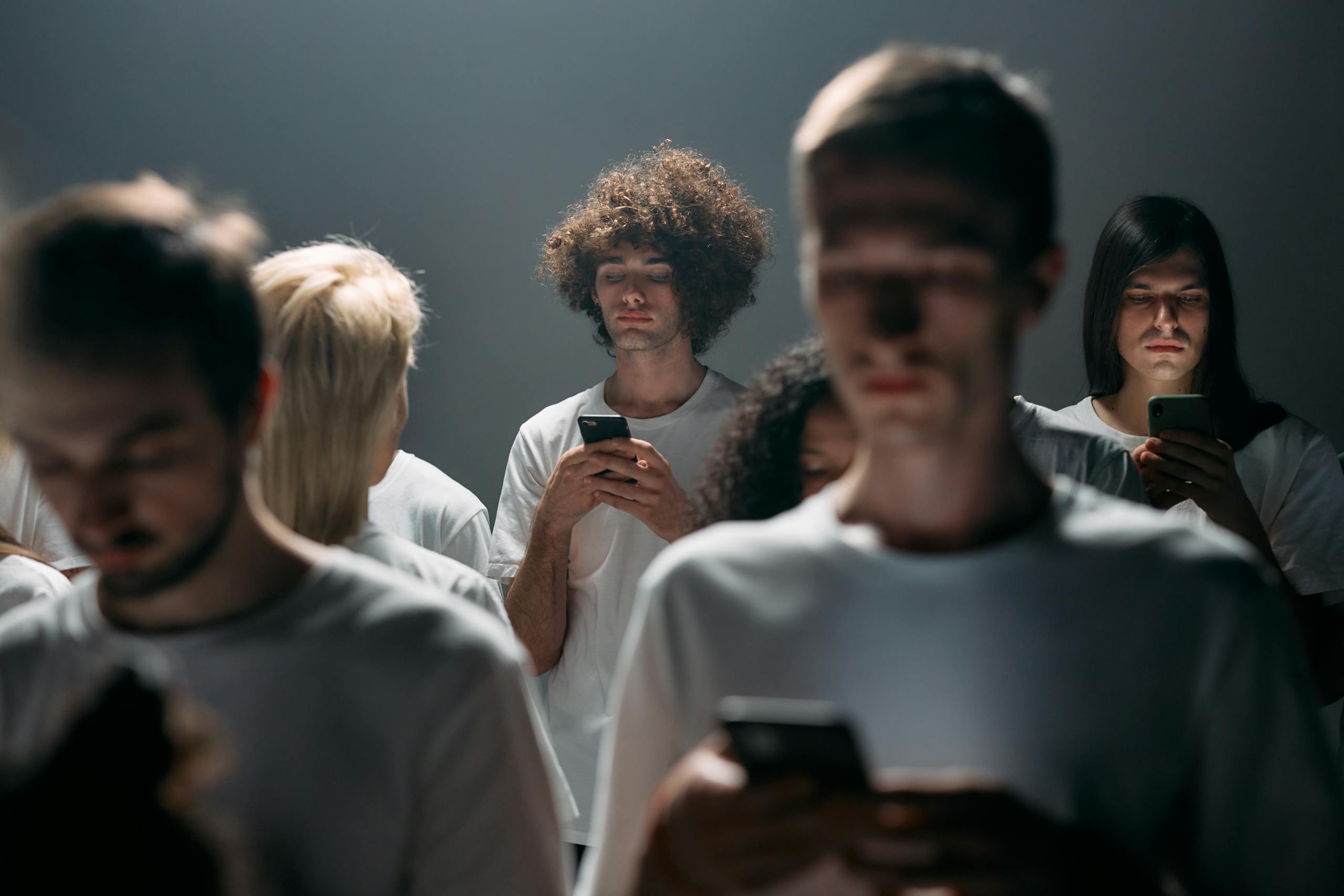 Sotwe: The Hidden Force Reshaping Culture, Technology, and Human ConnectionsGroup of young adults absorbed in smartphones under dramatic lighting, illustrating social isolation.