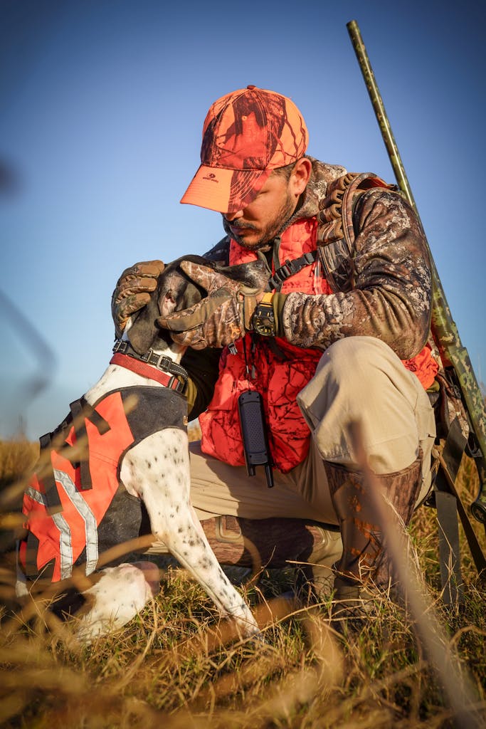 Hunter in camouflage affectionately holding hunting dog in field, Florida.
