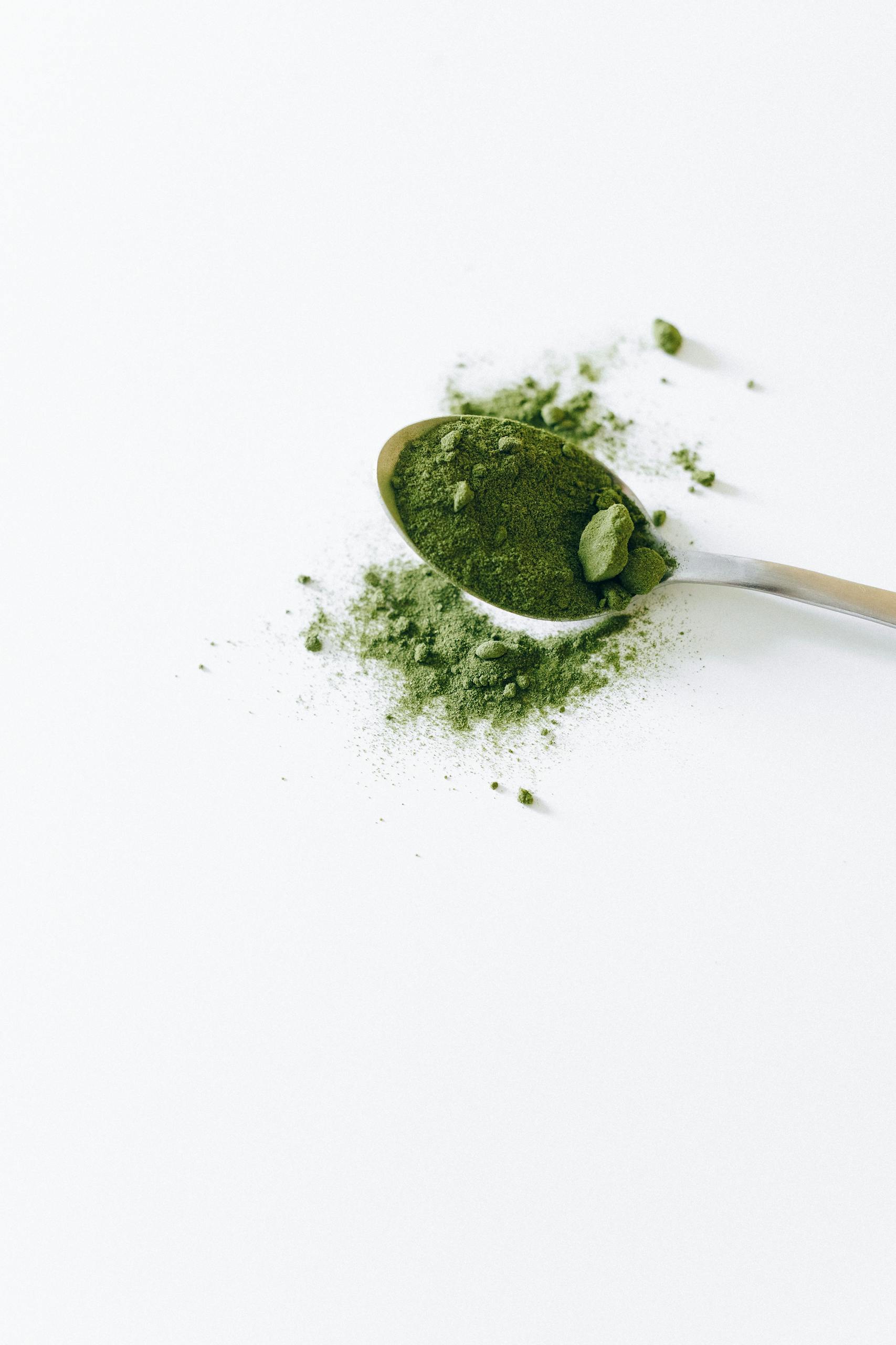 Bin Matcha: The Ultimate Guide to Premium Matcha Preservation, Flavor, and WellnessTop view of organic matcha powder on a silver spoon with a white background.