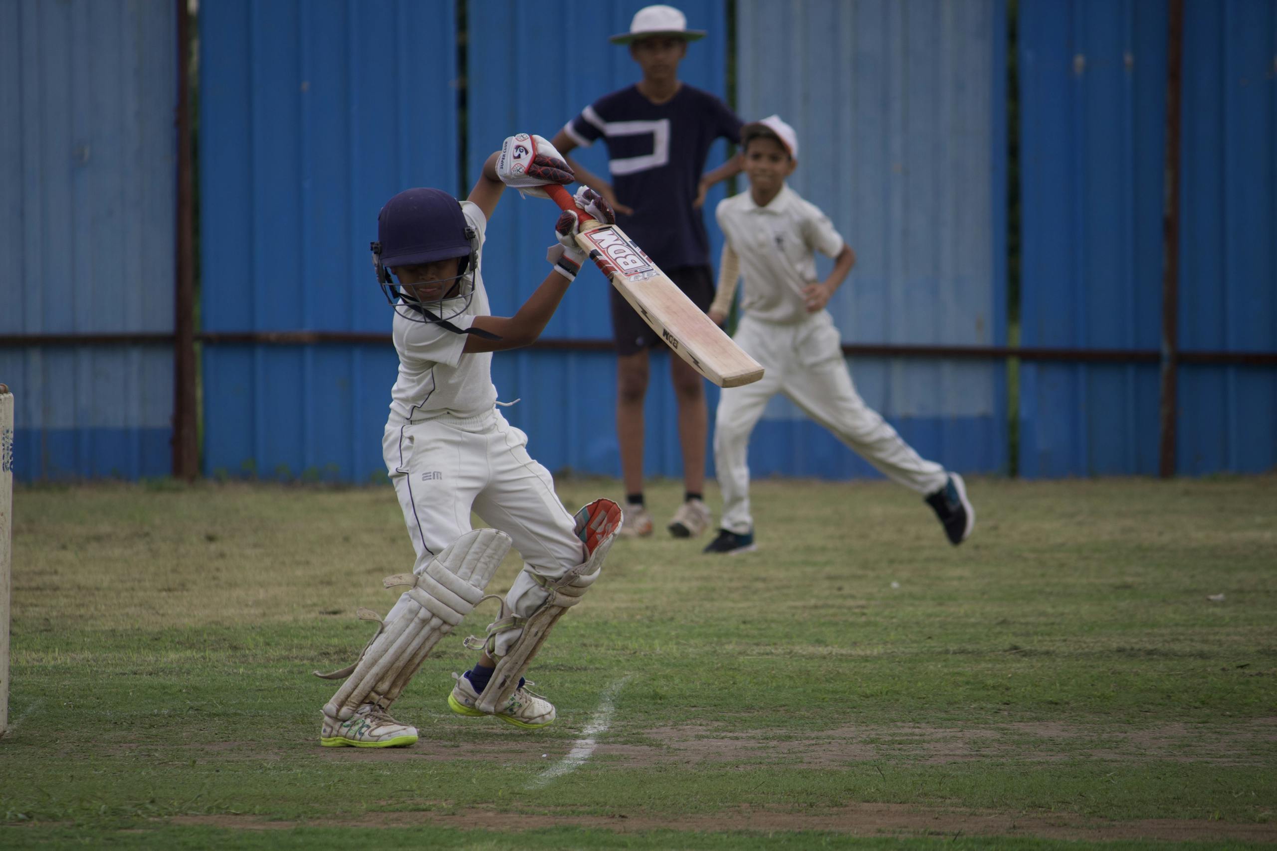 Pak vs Ind Young boys playing a competitive cricket match at Gahunje, showcasing teamwork.