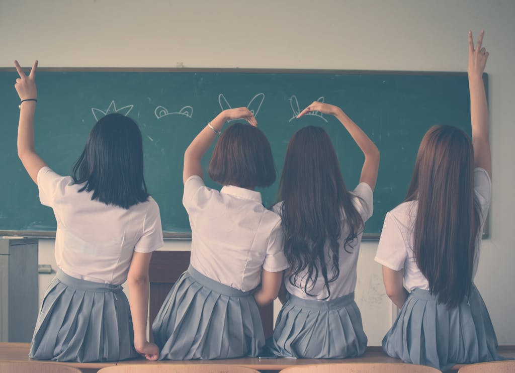 algebra.learning nexus.one of teenage girls in school uniforms enjoying time together in a classroom, posing with playful gestures.