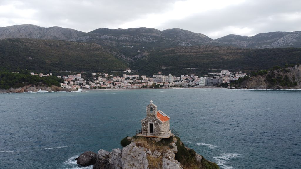 veb vatsap com A breathtaking drone shot over Petrovac, showcasing a historic church on the Adriatic coast.