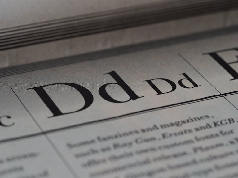 BlogBuzzNews.com Detailed close-up of a newspaper showing typography and lettering design.