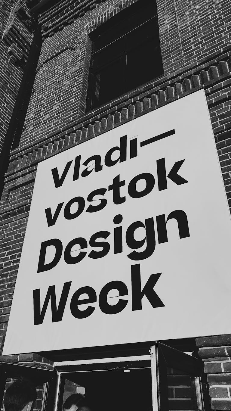 BCN Play Grayscale photo of Vladivostok Design Week signage on a building facade.