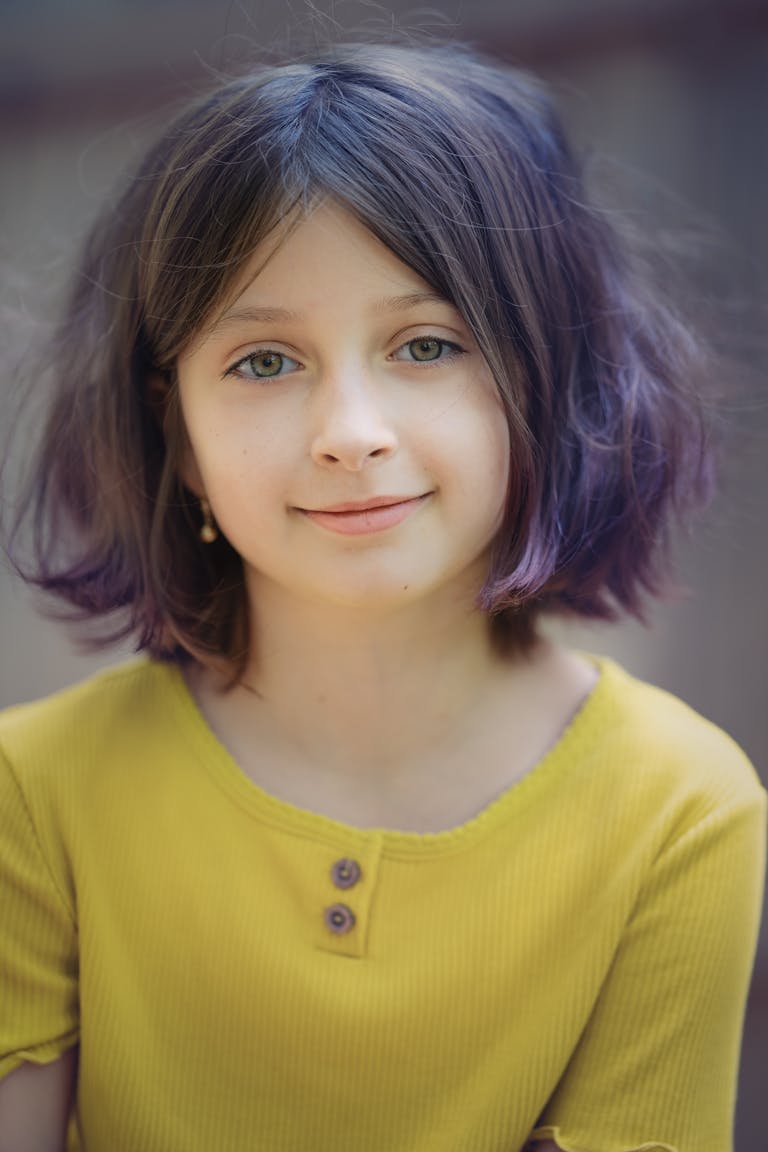 Finley Elaine Griffin A captivating portrait of a young girl with short hair smiling warmly, wearing a yellow shirt.