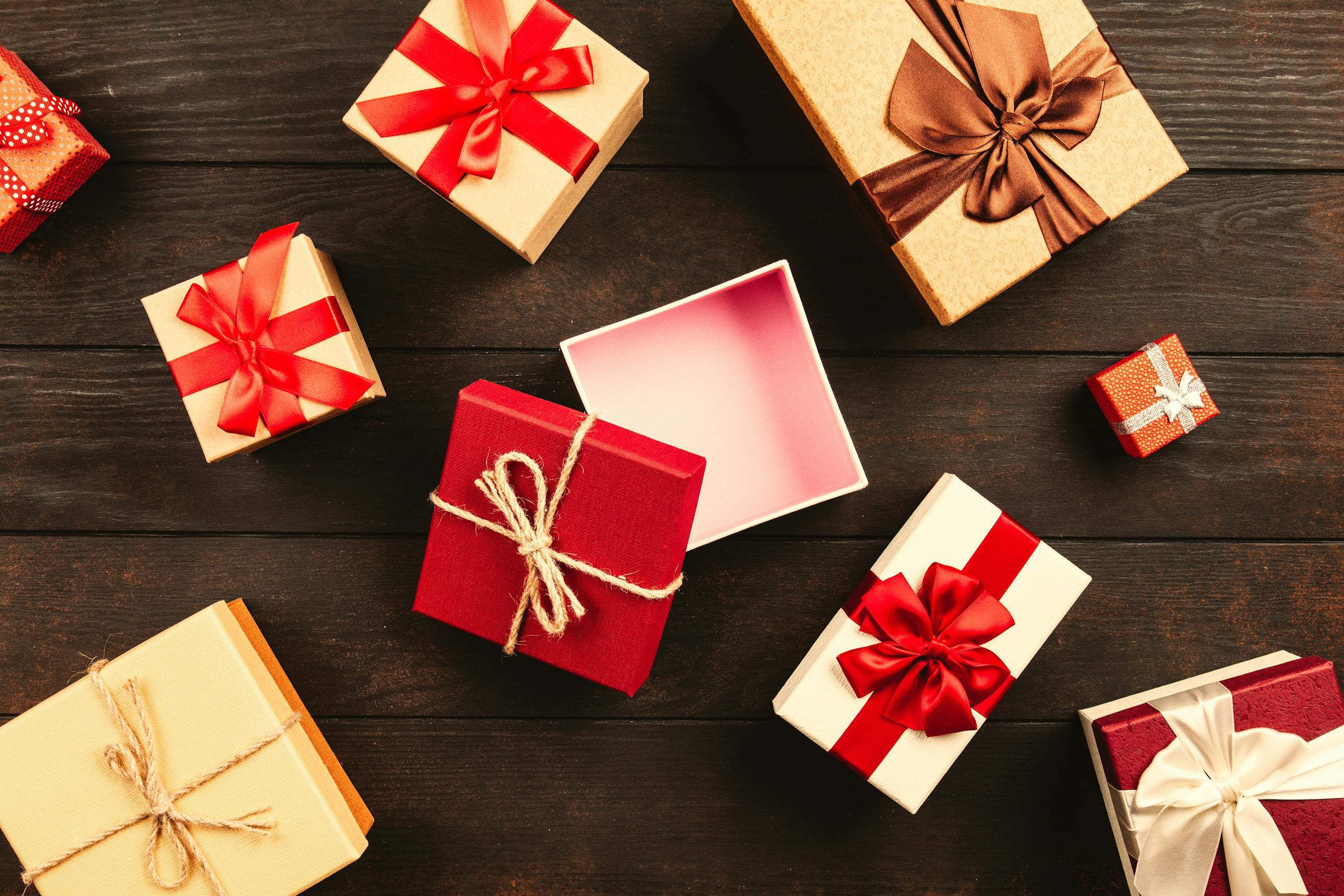 WhatUTalkingBoutWillis Gift Guide A festive flat lay of various Christmas presents adorned with colorful ribbons on a wooden background.