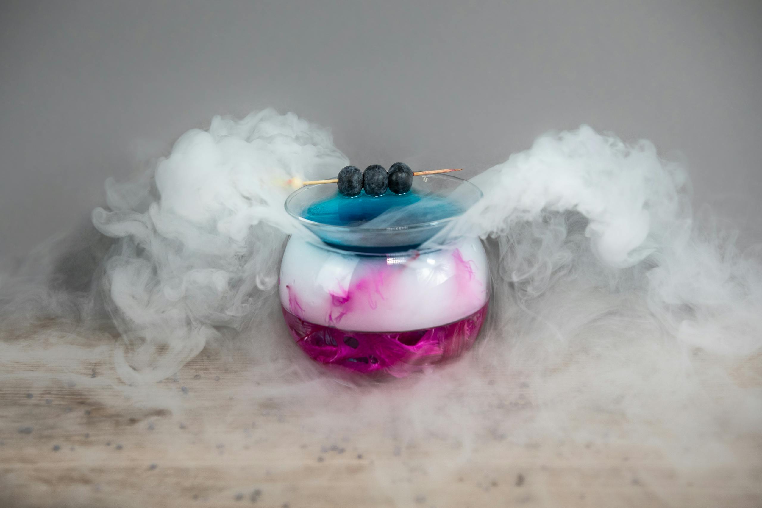 Nitrogen Artistic cocktail presentation with berries and smoke on gray background.