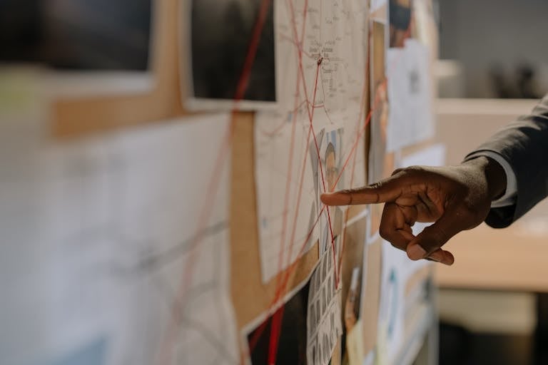 Century Link Close-up of an investigator pointing at an evidence board with connected clues using red strings.