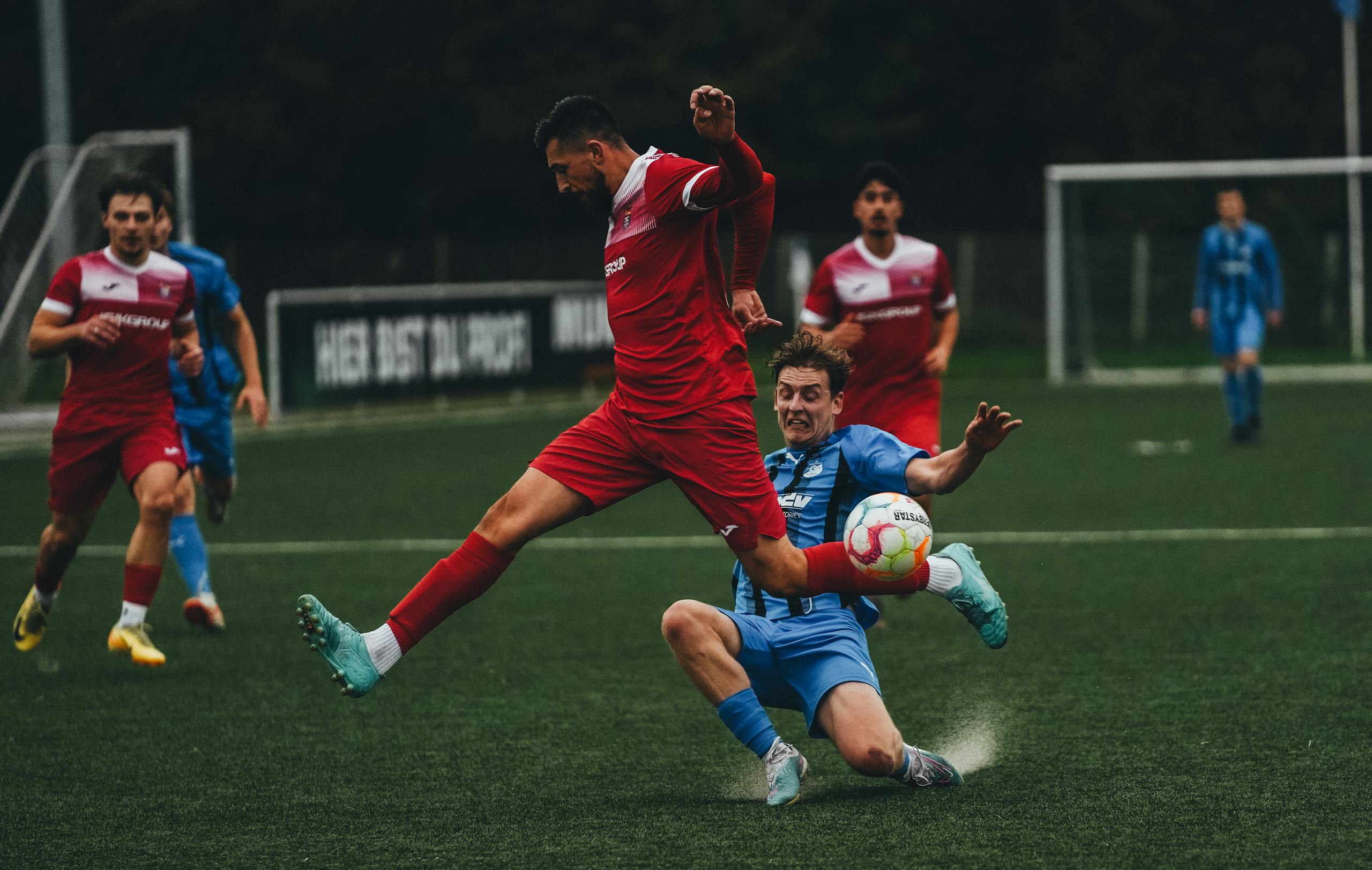 StreamEast Soccer Intense soccer match with players in mid-jump and tackle on a green field. Captivating sports action.