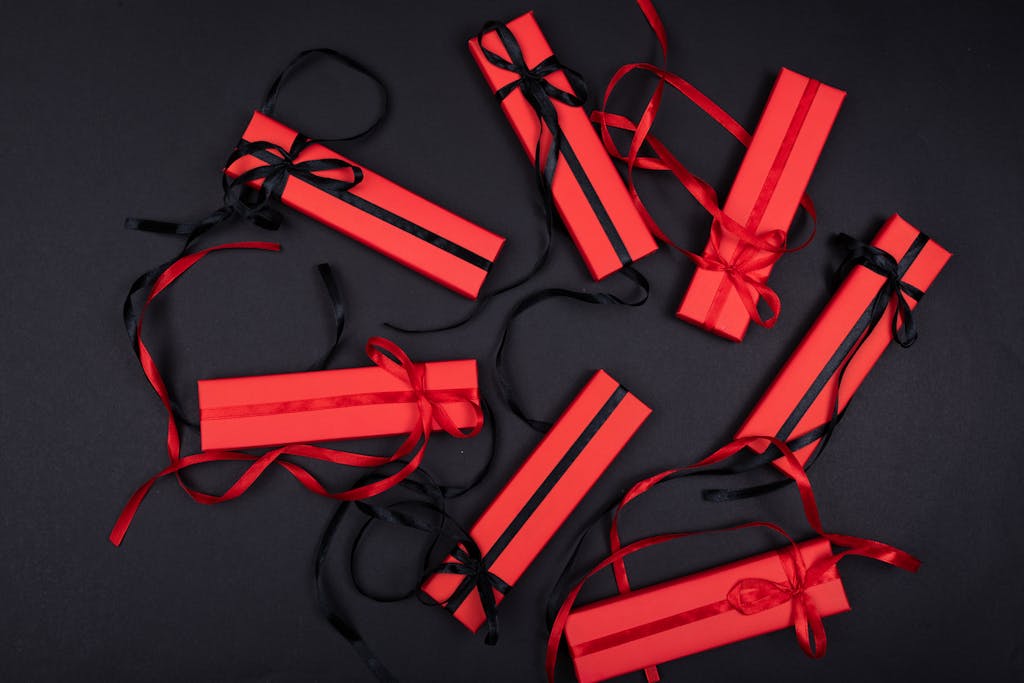 WhatUTalkingBoutWillis Gifts Top view of luxurious red gift boxes with black ribbons on a black background.